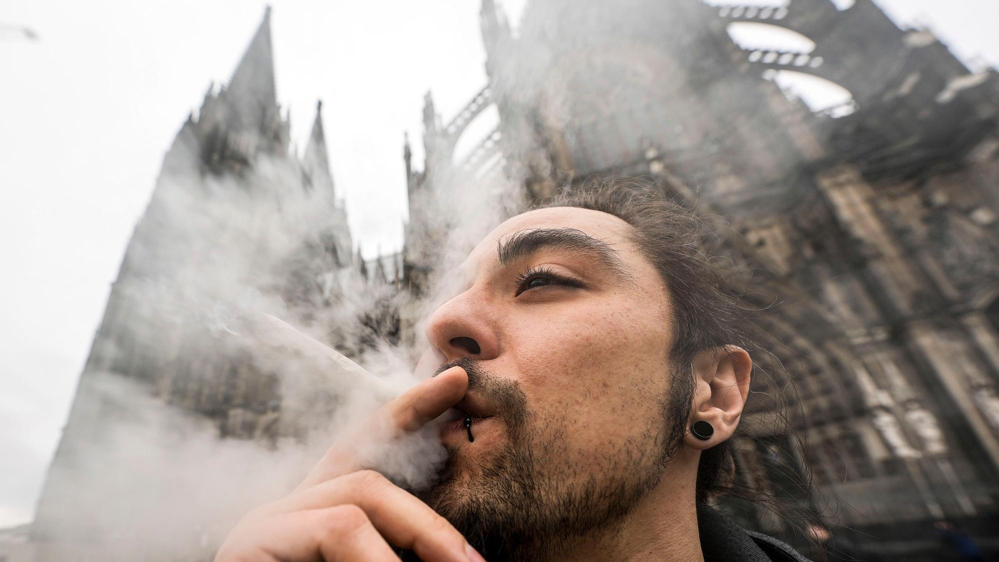 Ein Mann raucht vor dem Kölner Dom einen Joint.
