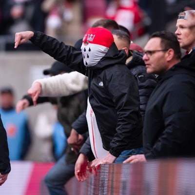Anhänger des 1. FC Köln gestikulieren nach der Partie am Spielfeldrand in Richtung der Mannschaft und teilen ihren Ärger über die Niederlage.