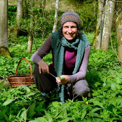 Naturpädagogin Jasmin Khalil kniet inmitten von Bärlauchpflanzen im Wald.