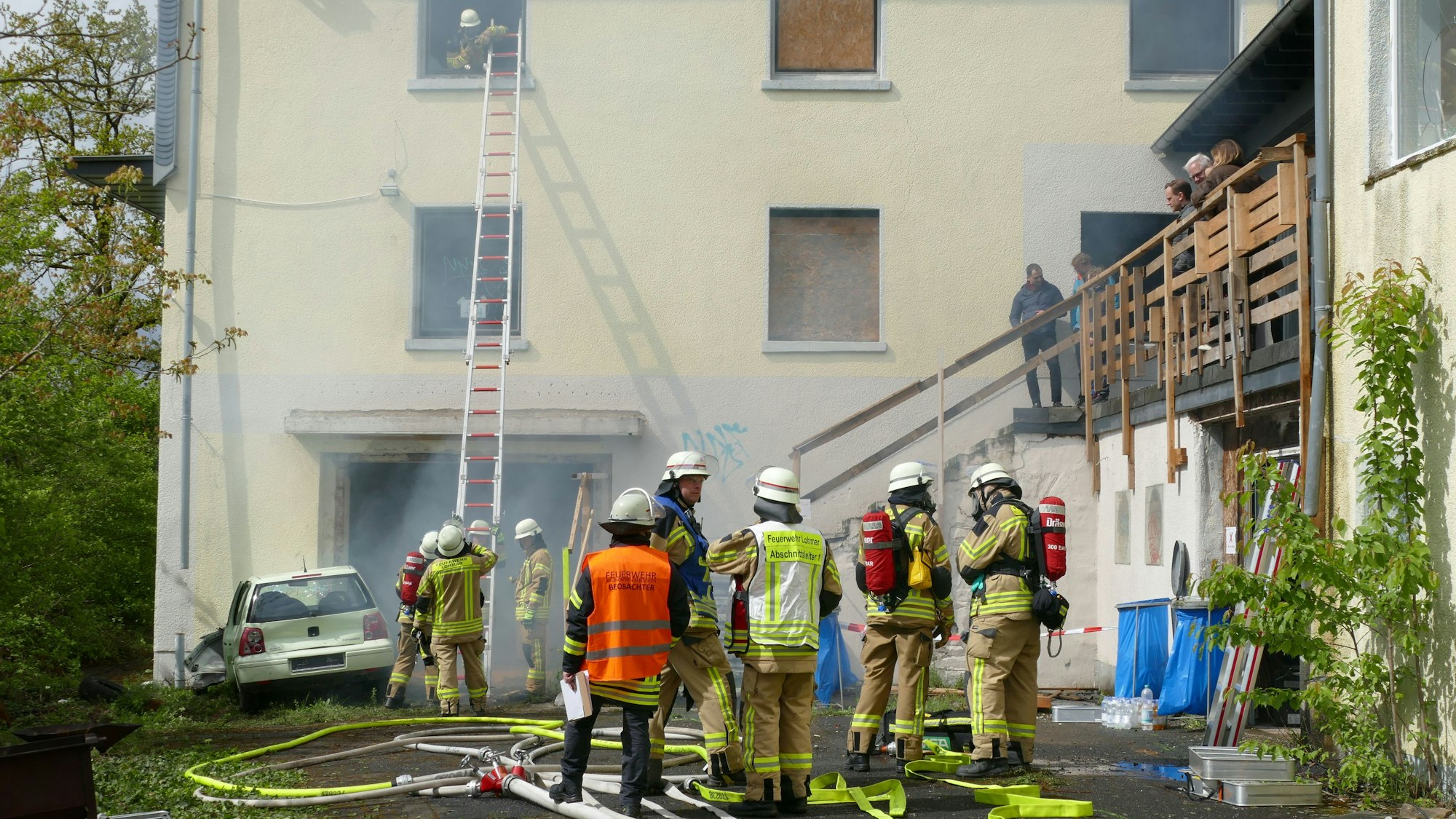 Feuerwehrleute haben eine Leiter an ein Haus gestellt, aus dem Qualm kommt.