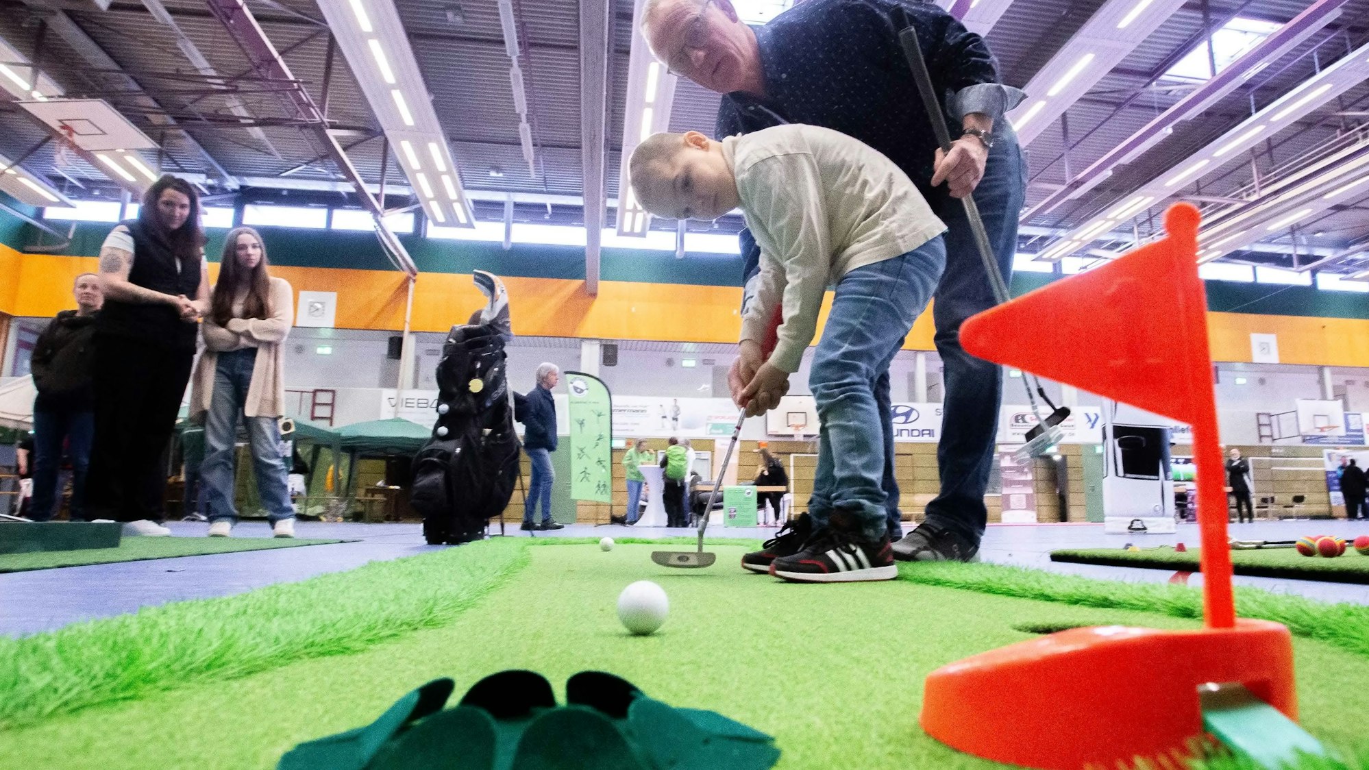 So wird's gemacht: Uwe Alefelder von der Gummersbacher Golfanlage „Gimborner Land“ gibt Tipps für die ersten Schläge. Hier steht er dem fünfjährigen Miles zur Seite.