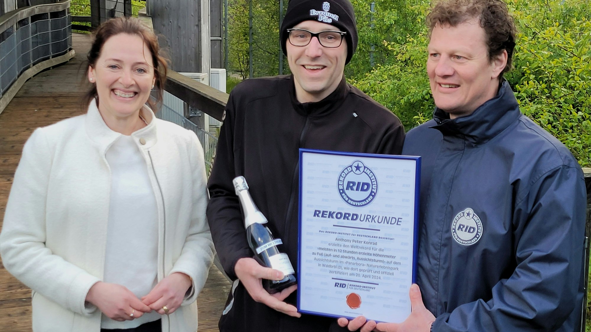 Im Waldbröler Naturerlebnispark Panarbora hat Anthony Peter Konrad (Mitte) am Samstagabend endlich den Weltrekord geschafft, ihm gratulieren Waldbröls Bürgermeisterin Larissa Weber und Maik Kaufmann vom Rekord-Institut für Deutschland.