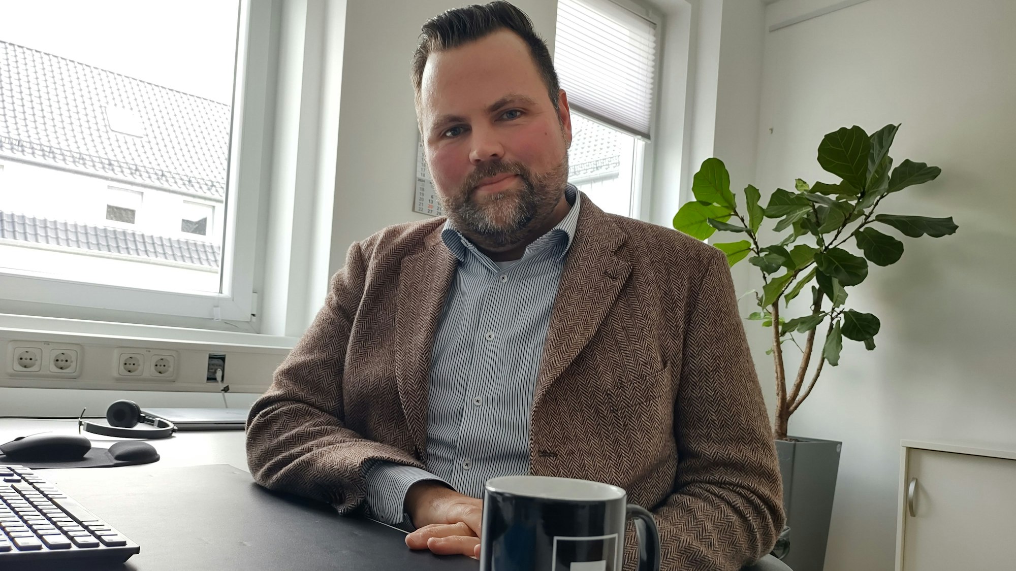 Michael Kehren sitzt an seinem Büroschreibtisch. Vor ihm steht ein schwarzer Kaffeebecher.