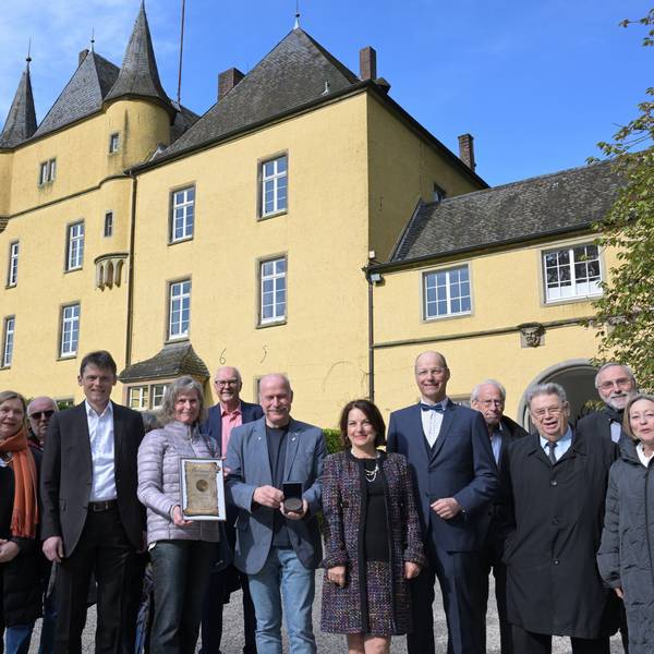 Schloß Strauweiler in Odenthal. Davor eine Gruppe von Menschen.