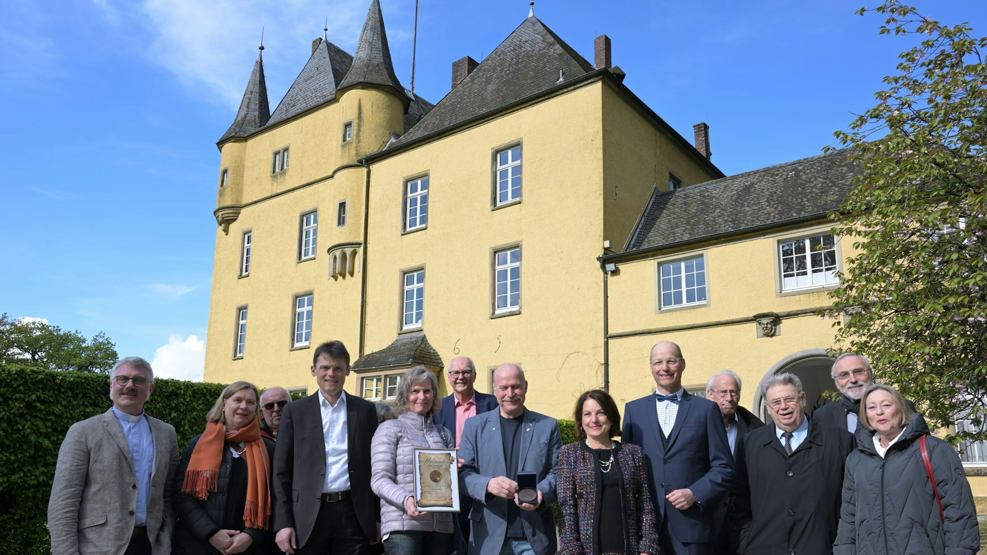 Schloß Strauweiler in Odenthal. Davor eine Gruppe von Menschen.
