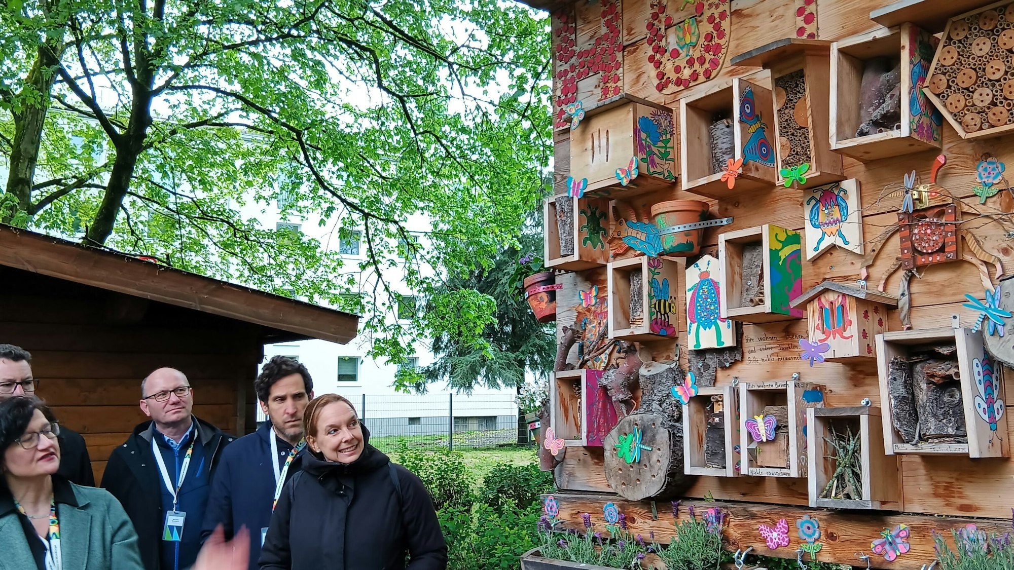 Eine Gruppe von Menschen vor einem Insektenhotel.
