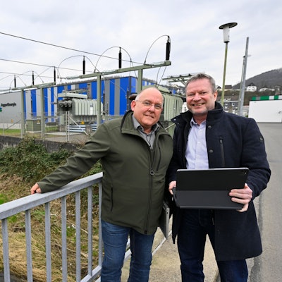 Zwei Männer stehen an einem Werk der Aggerenergie nebeneinander.