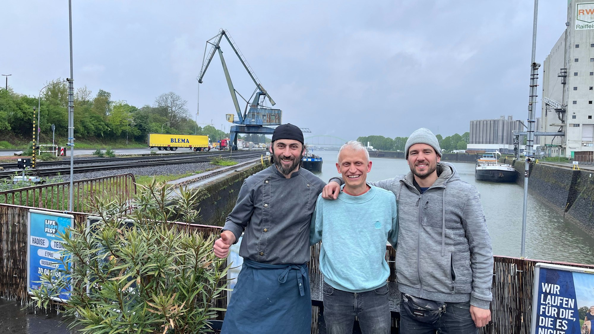 Erkan Karakas, Inhaber der Erkantine, Philip Minettos vom Verein Rosarot und Unterstützer Mario Sroka freuen sich auf das „Vrühlingsfest“ am Niehler Hafen.
