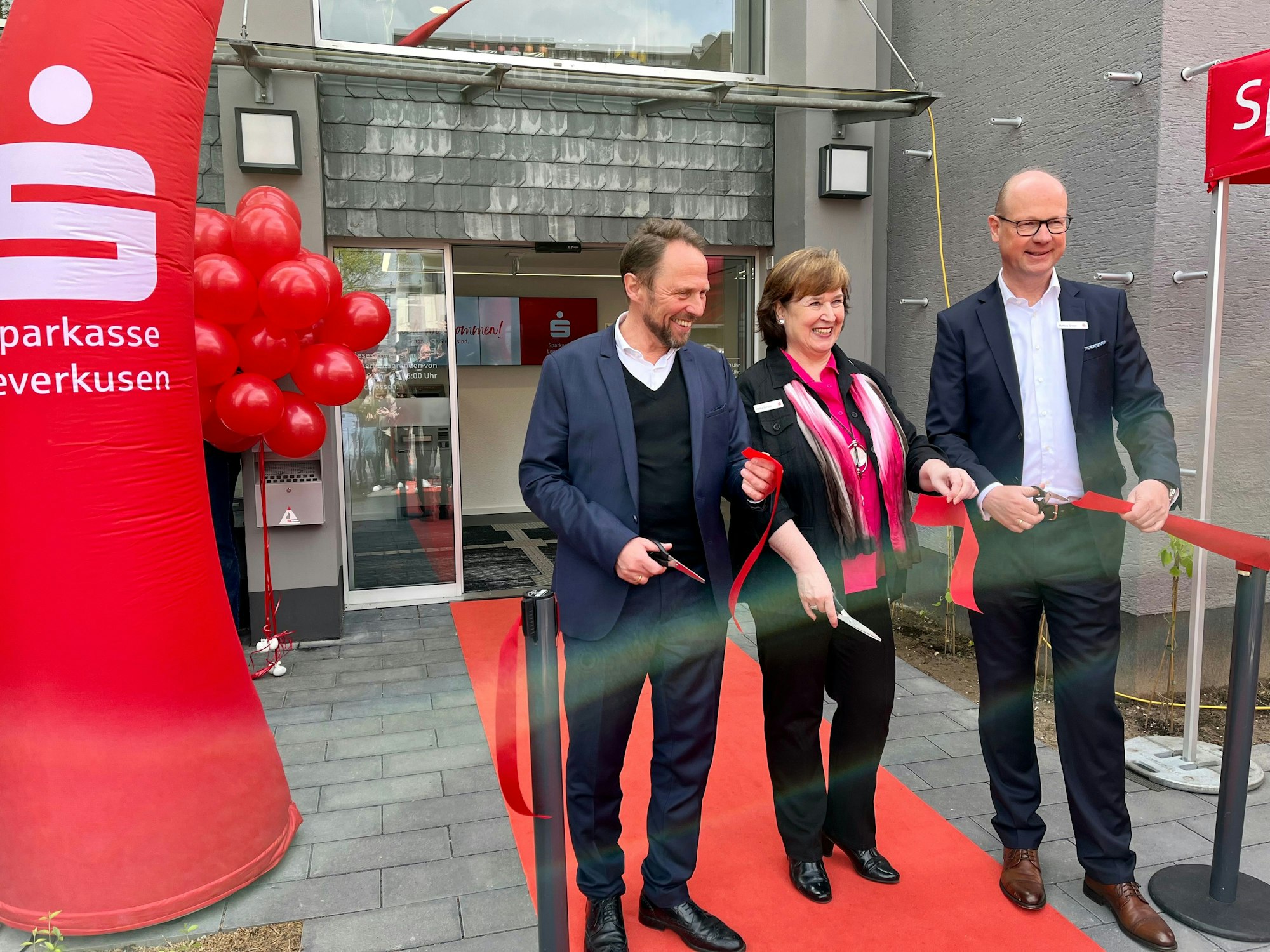 Im April 2024 eröffneten Filialleiterin Heike Schulz, Vorstand Markus Grawe (rechts) und der damalige OB Uwe Richrath in seiner Rolle als Vorsitzender des Verwaltungsrats die umgebaute Filiale der Sparkasse in Lützenkirchen.