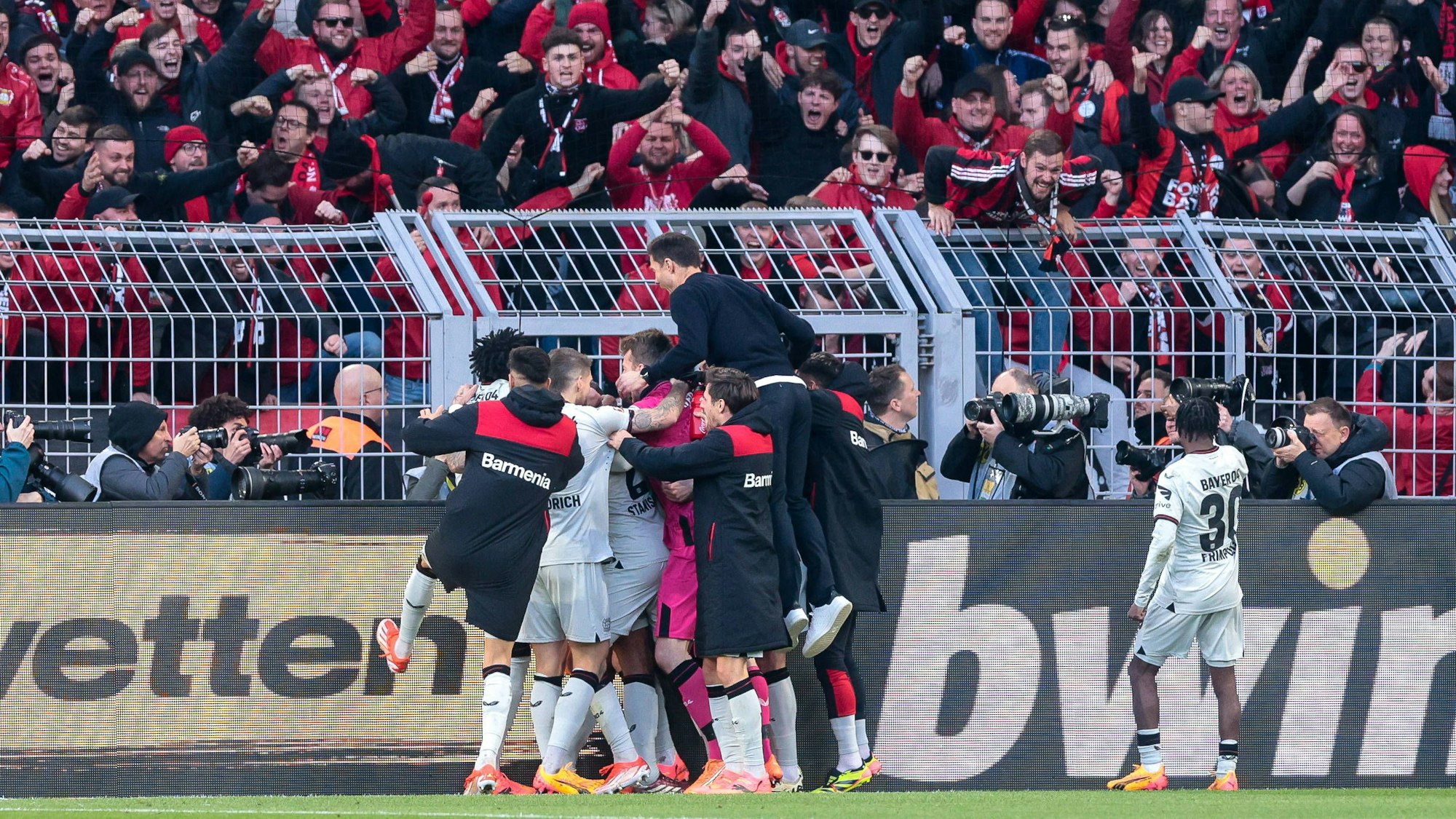 Die Leverkusener bejubeln vor den angereisten Fans den späten Ausgleichstreffer durch Josip Stanisic. Trainer Alonso wirft sich auf die Jubeltraube.