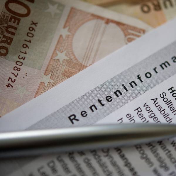 Ein Kugelschreiber und ein Geldschein liegen auf einer Renteninformation, dem jährlichen Schreiben der Deutschen Rentenversicherung an alle Versicherten zu ihrer gesetzlichen Rente.