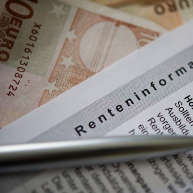Ein Kugelschreiber und ein Geldschein liegen auf einer Renteninformation, dem jährlichen Schreiben der Deutschen Rentenversicherung an alle Versicherten zu ihrer gesetzlichen Rente.