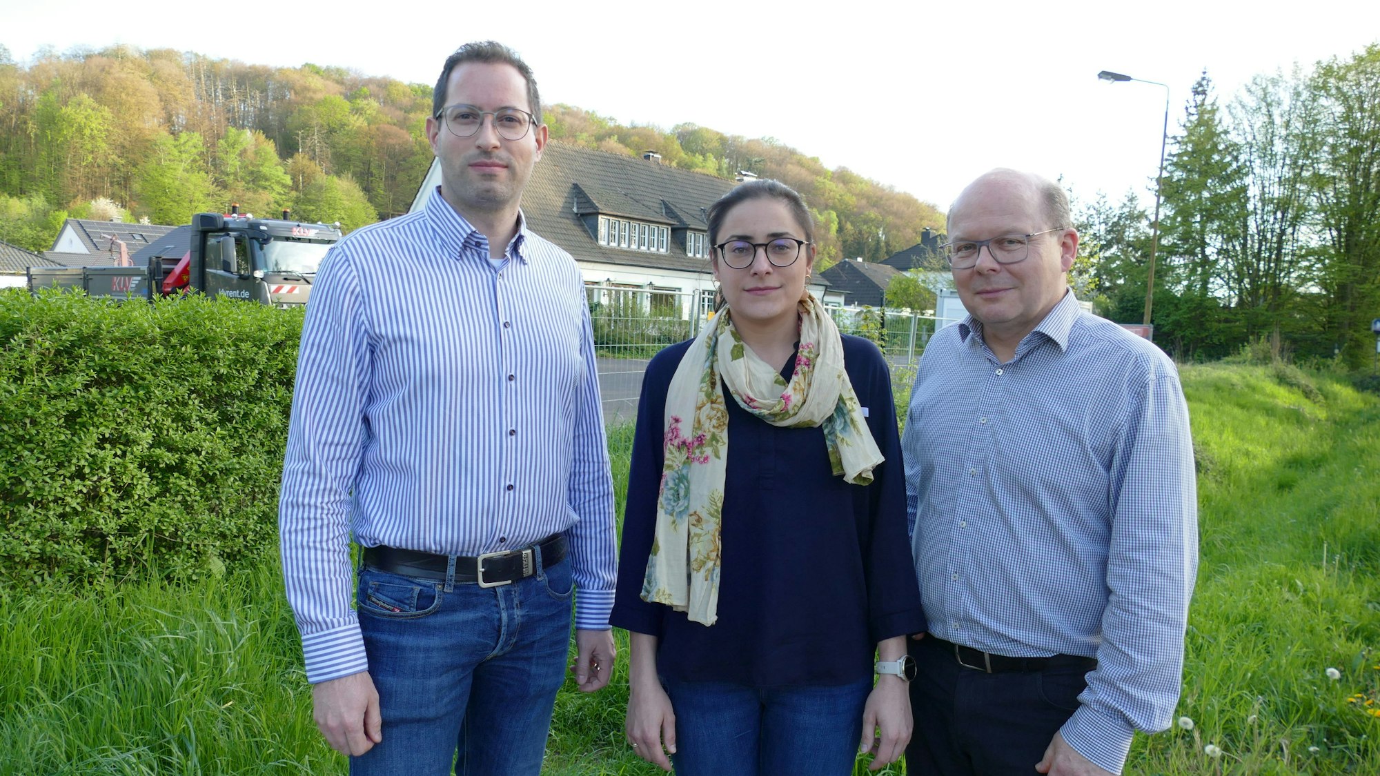 Drei Menschen stehen auf einer Wiese.