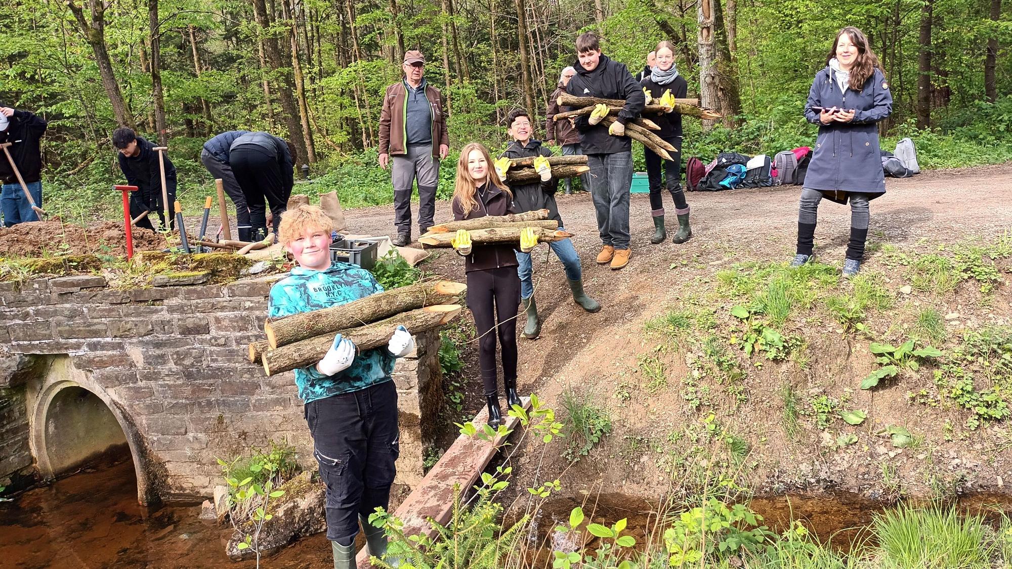 Jugendliche tragen angespitzte Holzstämme