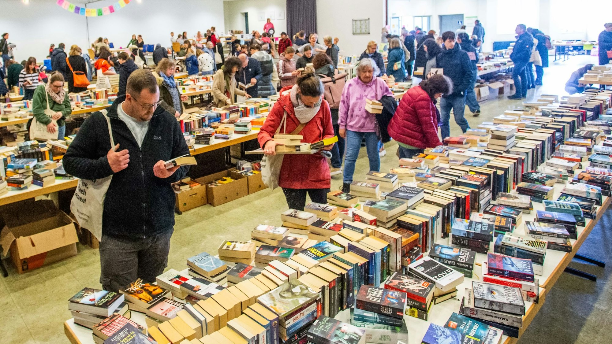 Blick in einer Halle, in der ein Bücherflohmarkt stattfindet.