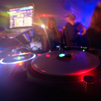 Partygänger tanzen vor einem DJ-Pult.