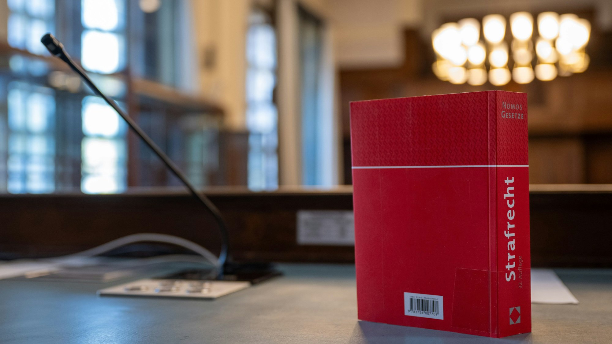 Das Gesetzbuch „Strafrecht“ steht auf einem Tisch in einem Verhandlungssaal.