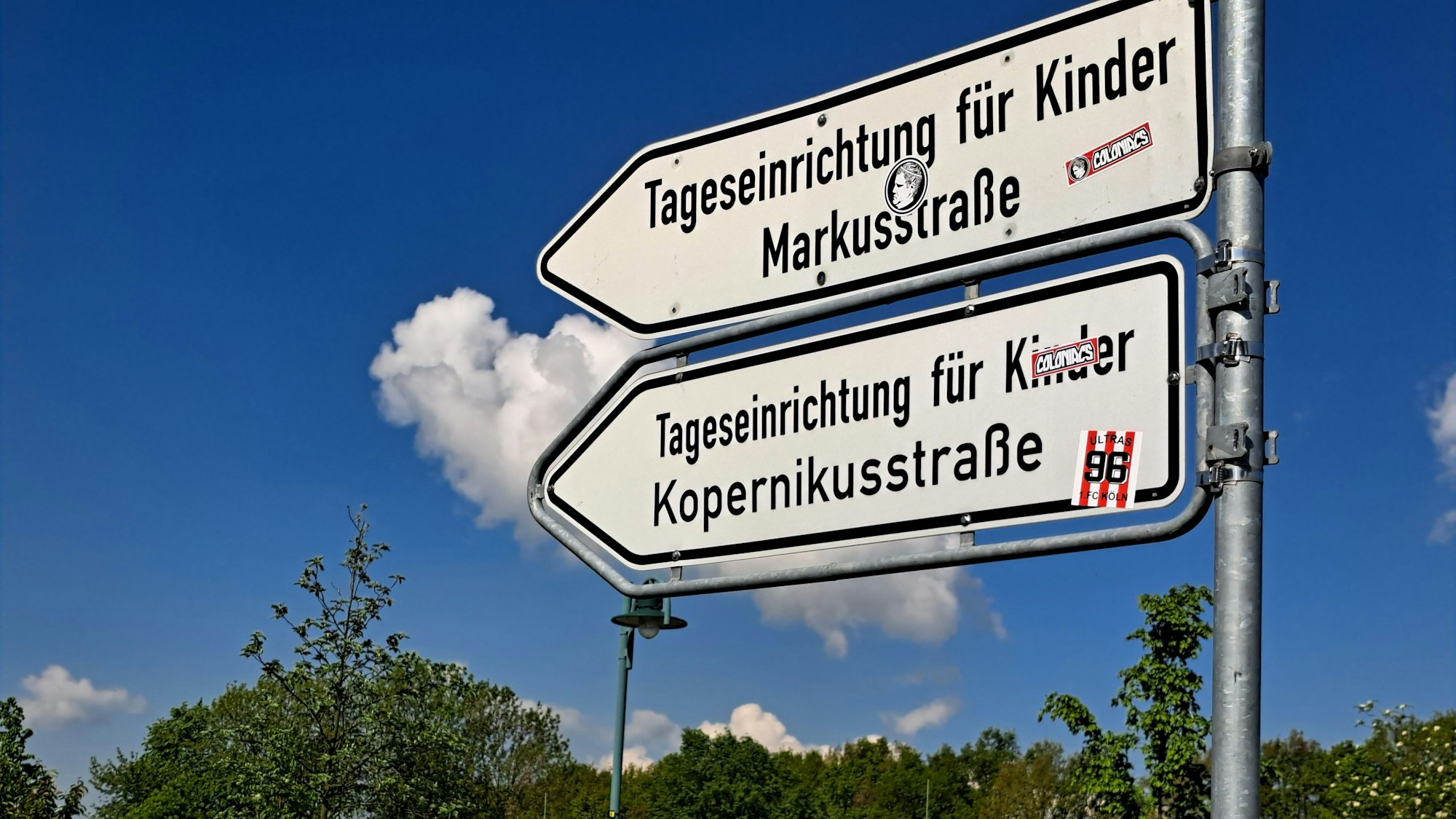 Hinweisschilder an einer Straße. Die Pfeile weisen auf eine Tageseinrichtung für Kinder Markusstraße und die Tageseinrichtung für Kinder Kopernikusstraße hin.