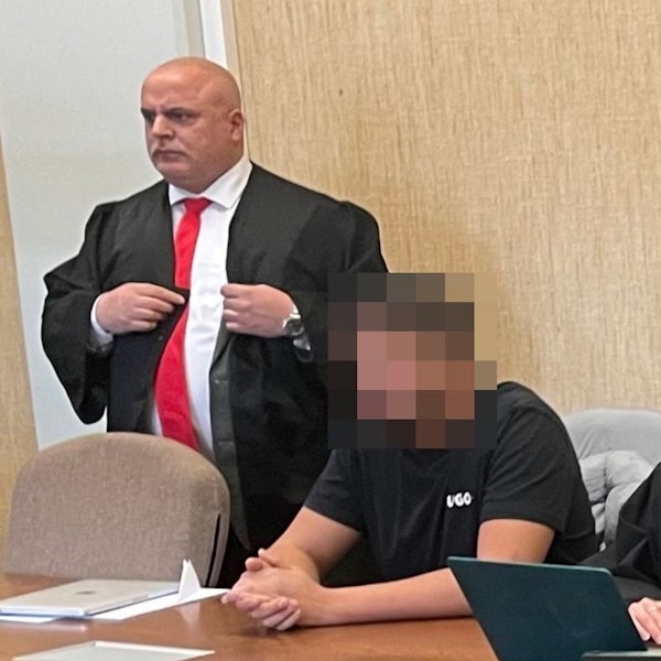 Zu sehen sind ein stehender und ein sitzender Mann in einem Gerichtssaal.