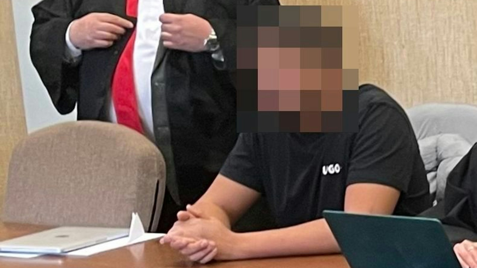 Zu sehen sind ein stehender und ein sitzender Mann in einem Gerichtssaal.
