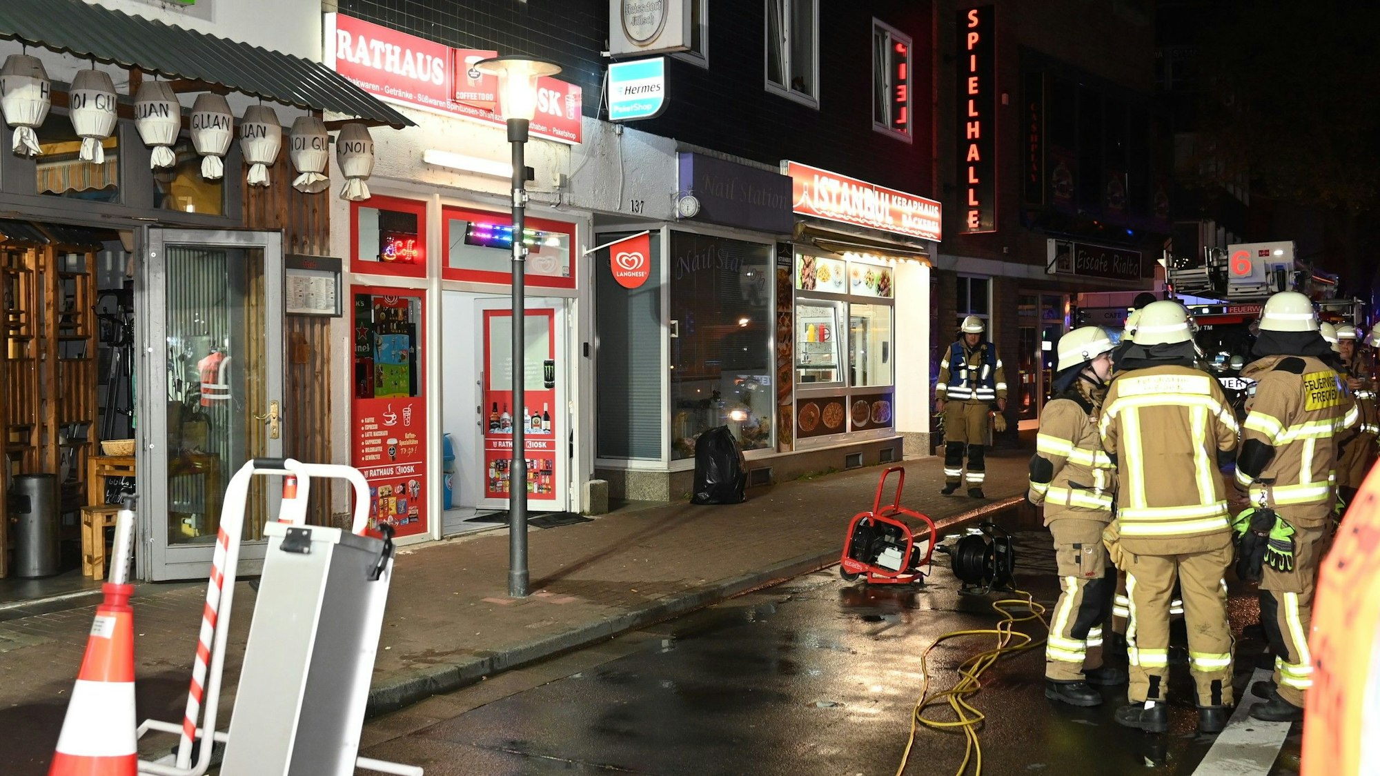Die Einsatzkräfte der Feuerwehr vor einem Laden auf der Hauptstraße in Frechen.