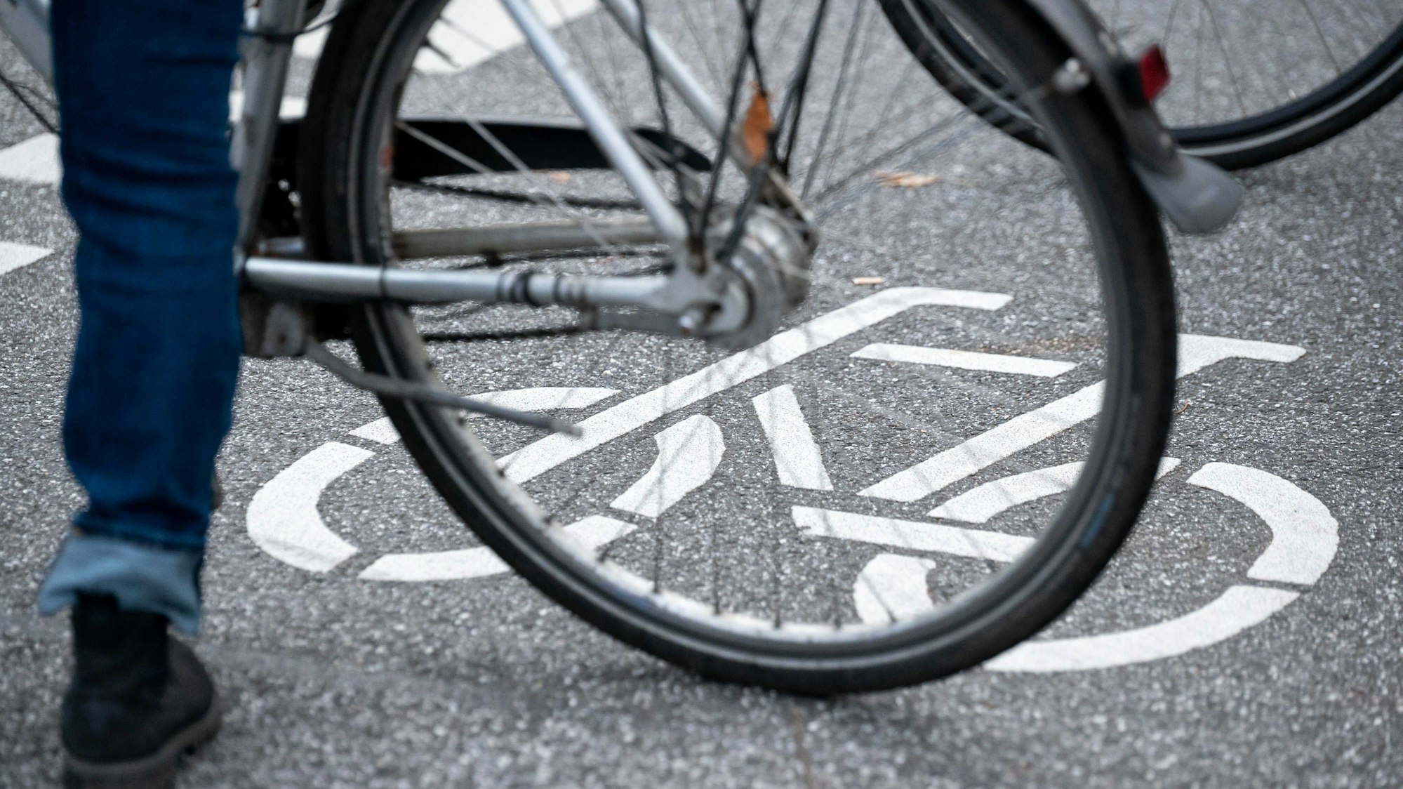 ARCHIV - 31.10.2021, Hamburg: Ein Fahrrad-Symbol ist auf der Fahrbahn einer Straße hinter einem Fahrrad zu sehen. (zu dpa: «14-jähriger Radfahrer stürzt und wird schwer verletzt») Foto: Jonas Walzberg/dpa +++ dpa-Bildfunk +++