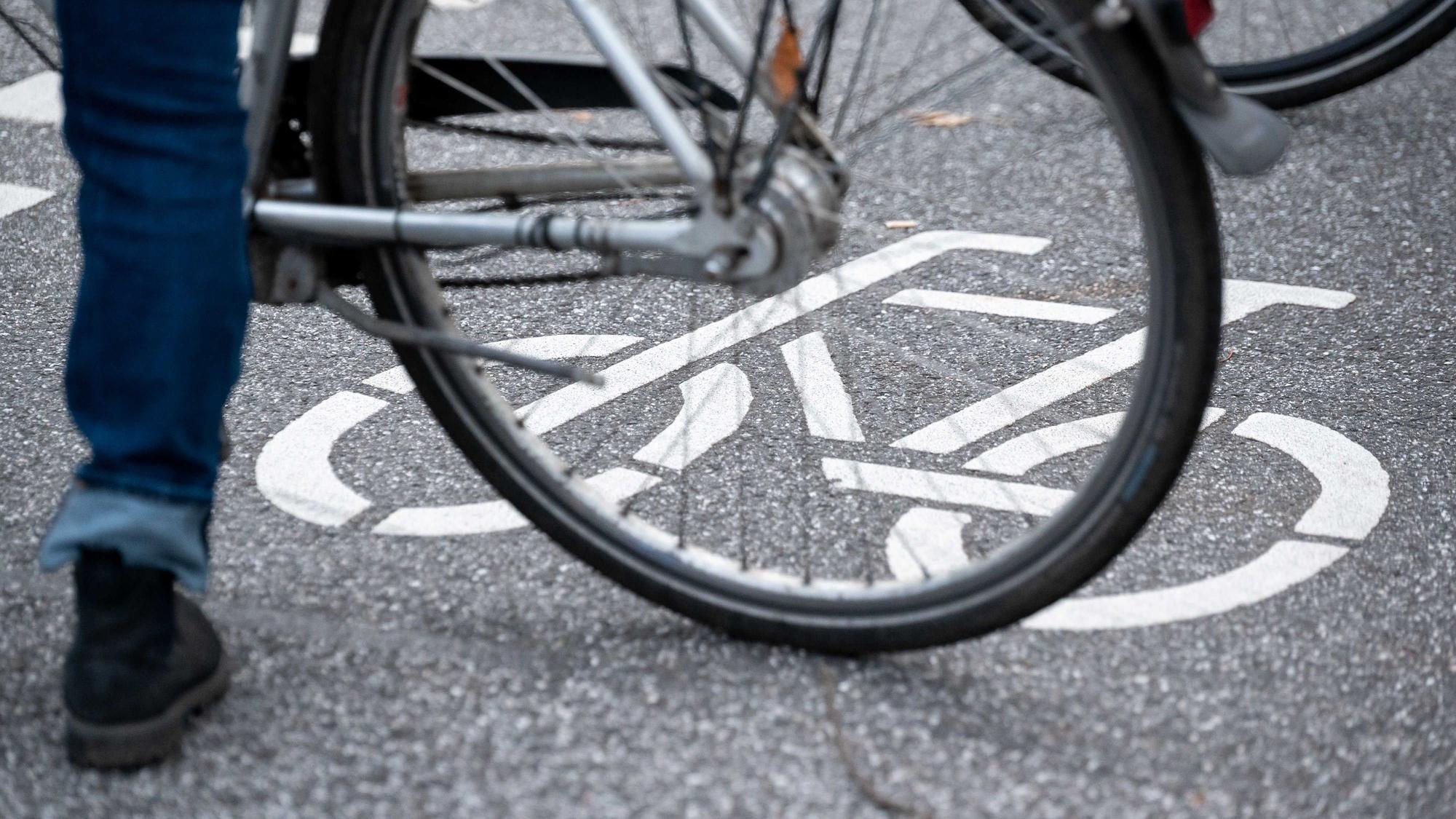 ARCHIV - 31.10.2021, Hamburg: Ein Fahrrad-Symbol ist auf der Fahrbahn einer Straße hinter einem Fahrrad zu sehen. (zu dpa: «14-jähriger Radfahrer stürzt und wird schwer verletzt») Foto: Jonas Walzberg/dpa +++ dpa-Bildfunk +++