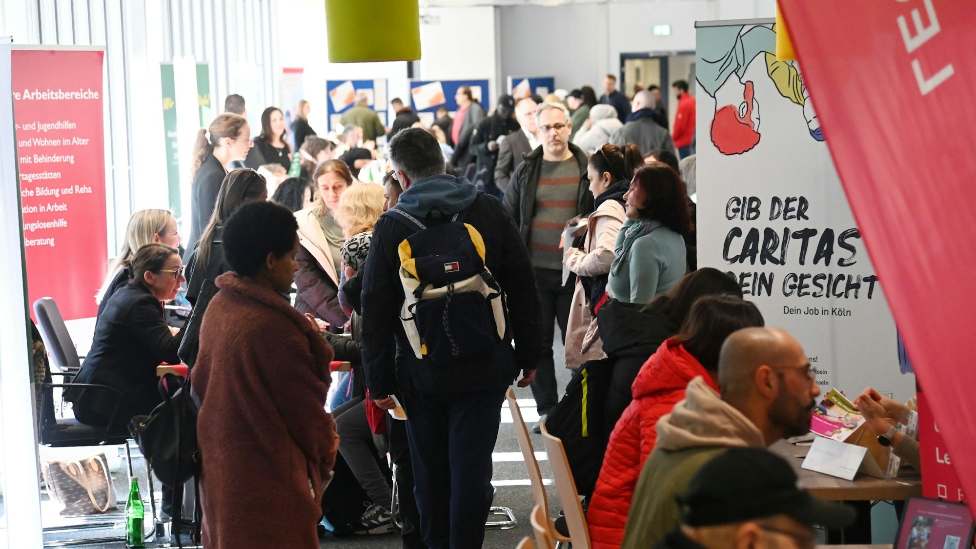 Menschen laufen zwischen Infoständen entlang.