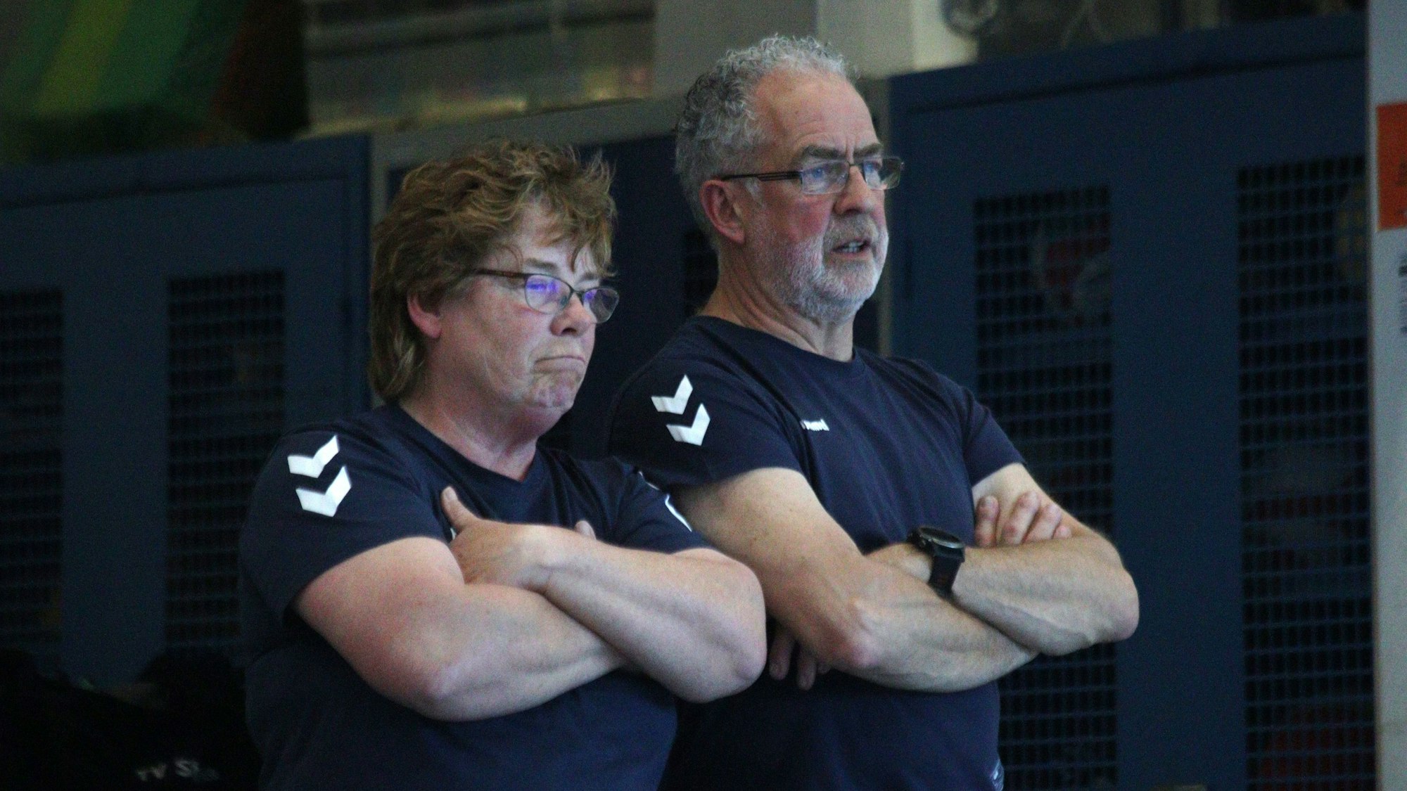 Die Trainer des TV Stotzheim, Evelin und Günter Buschkamp, beobachten mit verschränkten Armen und ernstem Gesichtsausdruck die drohende Niederlage.