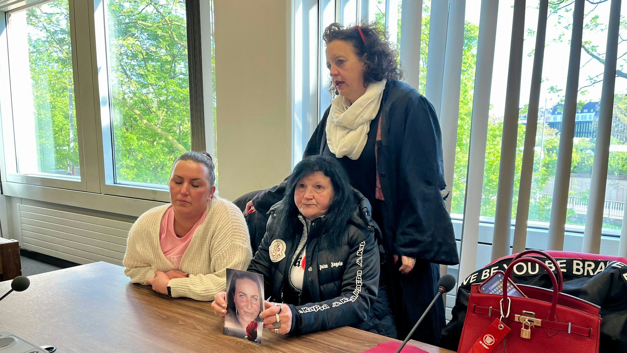 Schwester (links) und Mutter hatten zum Prozessauftakt ein Foto des Opfers mitgebracht. Vor nicht einmal sechs Monaten wurde die schwangere Frau von ihrem Freund auf offener Straße erstochen.