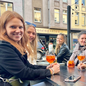Fünf junge Frauen im Straßenlokal trinken Aperol