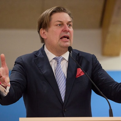 Maximilian Krah, Spitzenkandidat der AfD bei der Europawahl 2024, steht an einem Rednerpult vor einer blauen Leinwand mit dem Parteilogo.