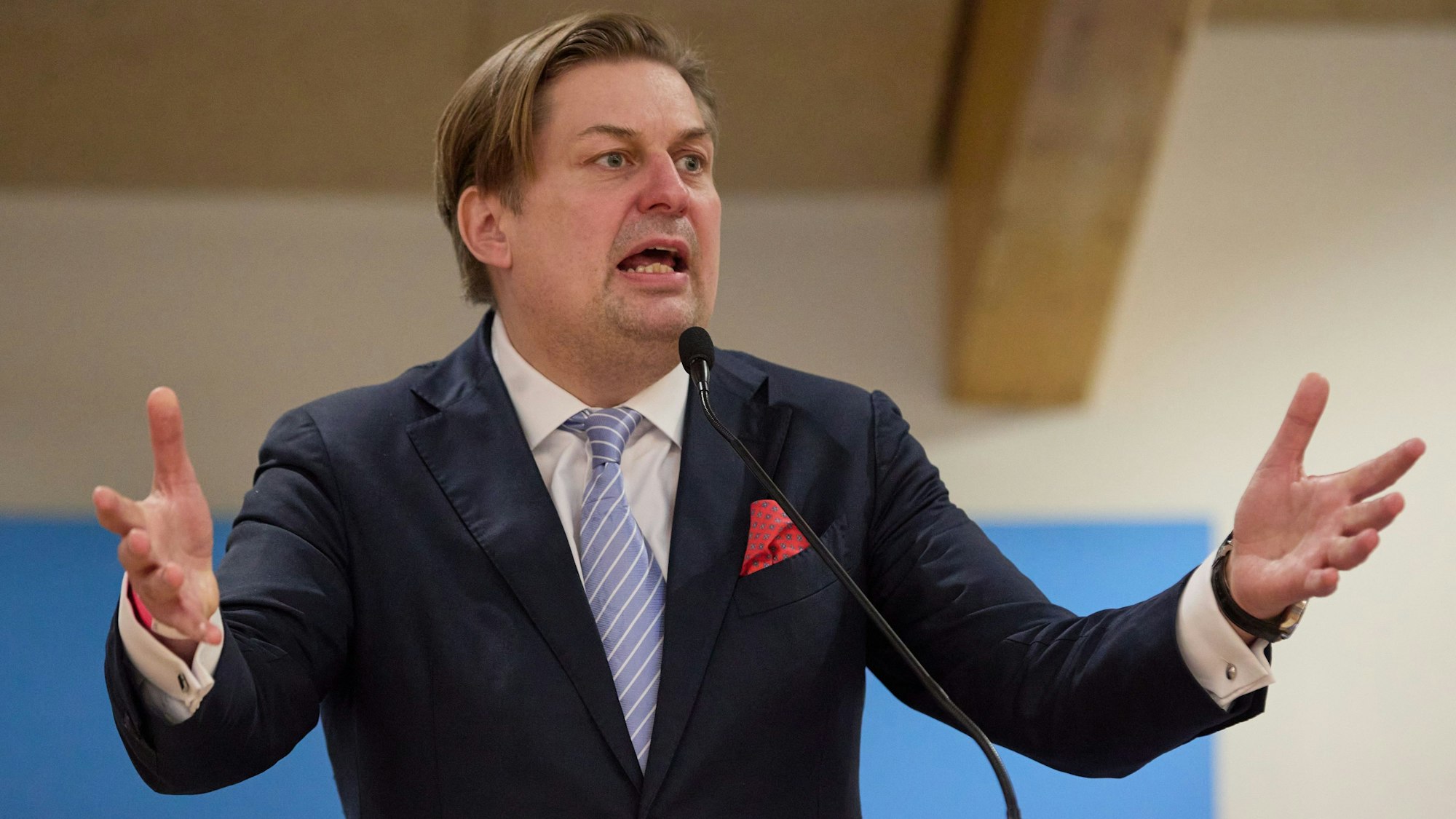 Maximilian Krah, Spitzenkandidat der AfD bei der Europawahl 2024, steht an einem Rednerpult vor einer blauen Leinwand mit dem Parteilogo.