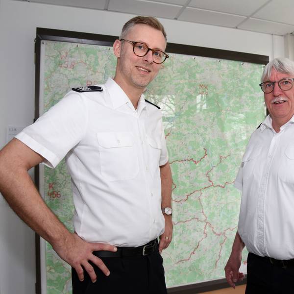 Der neue Kreisbrandmeister und scheidende Kreisbrandmeister Wilfried Fischer des Oberbergischen Kreises stehen vor einer Kreiskarte nebeneinander.