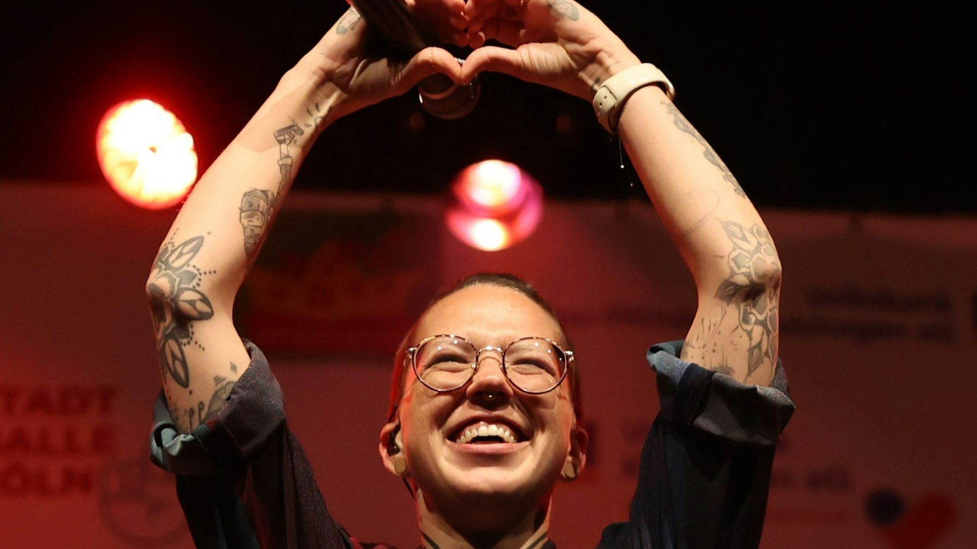 Die Sängerin Stefanie Heinzmann steht auf einer Bühne, formt ihre Hände zu einem Herz und lacht.