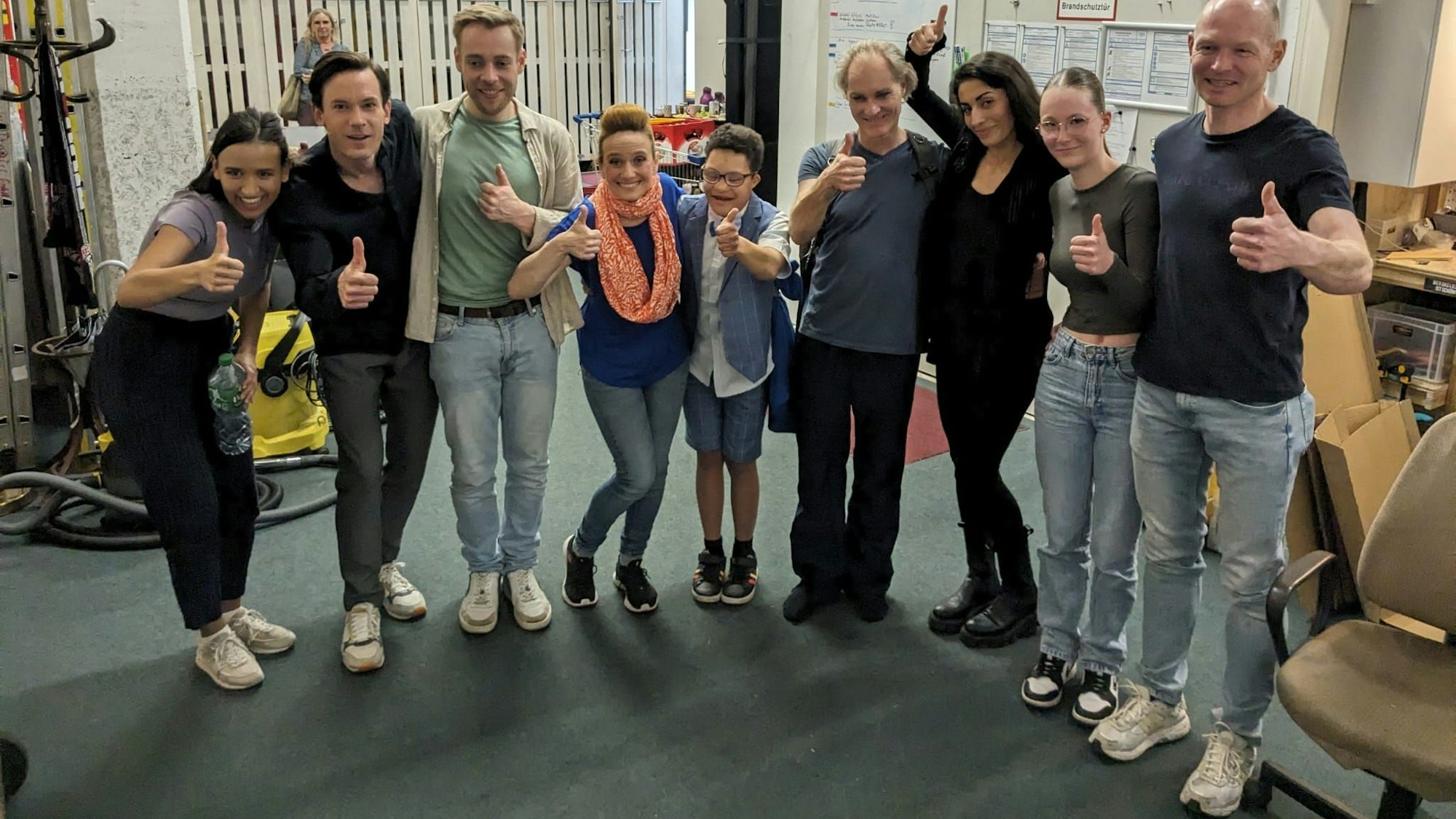 Eine Gruppe Menschen steht nebeneinander und posiert für ein Foto. Sie strecken den gereckten Daumen hoch.