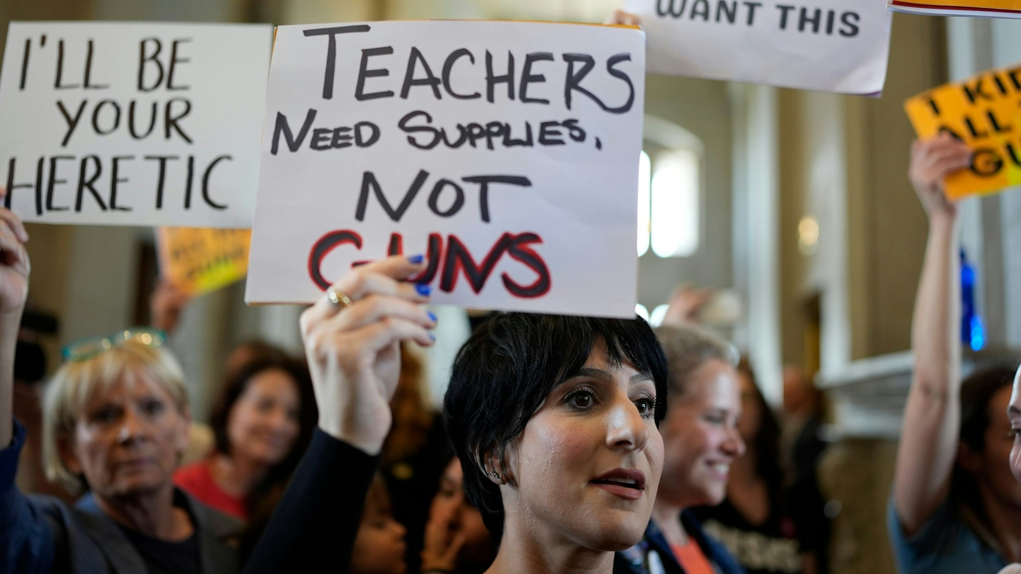 Menschen halten verschiedene Schilder gegen das neue Gesetz in die Höhe.