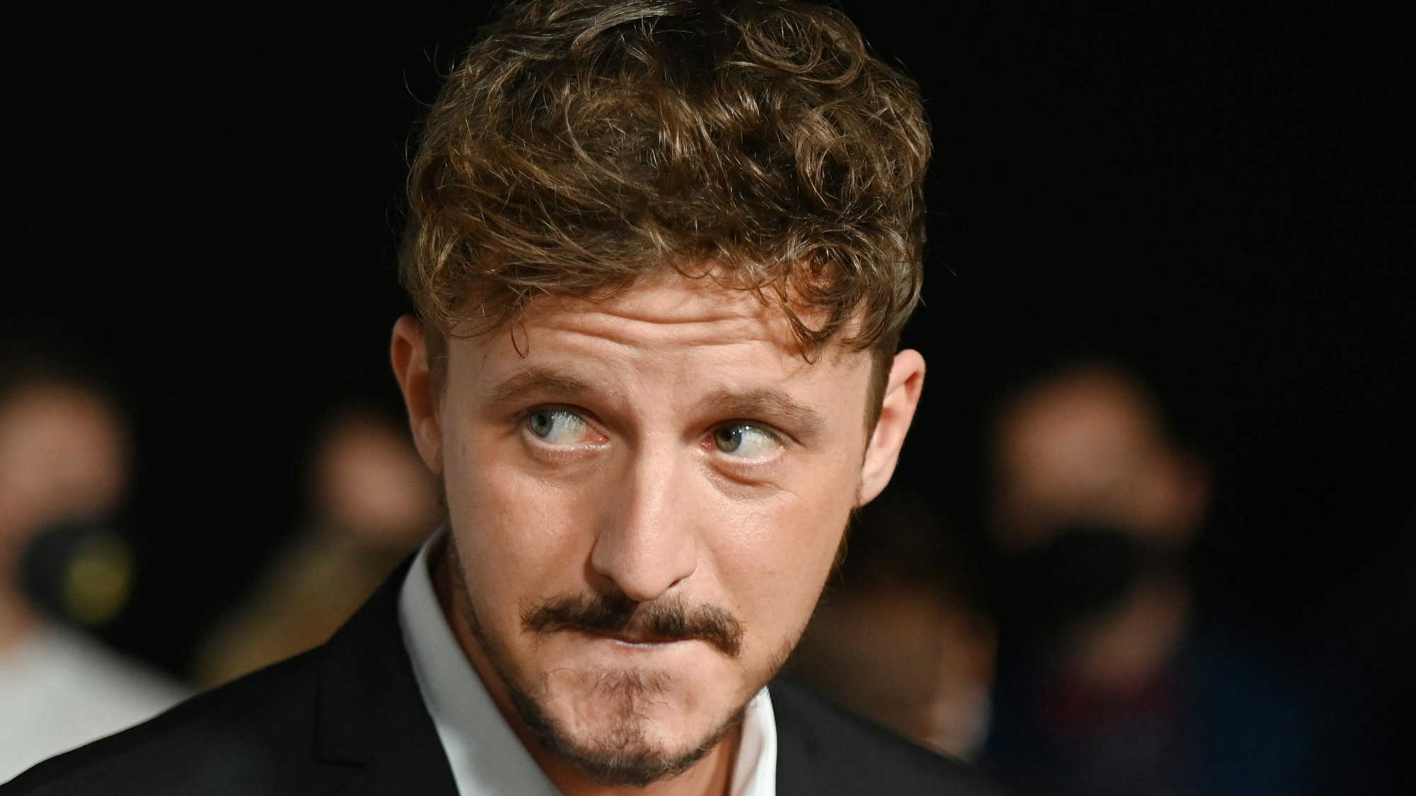 Tommi Schmitt, Autor und Moderator, steht bei einer Preisverleihung im Anzug auf dem Roten Teppich und gibt ein Interview.