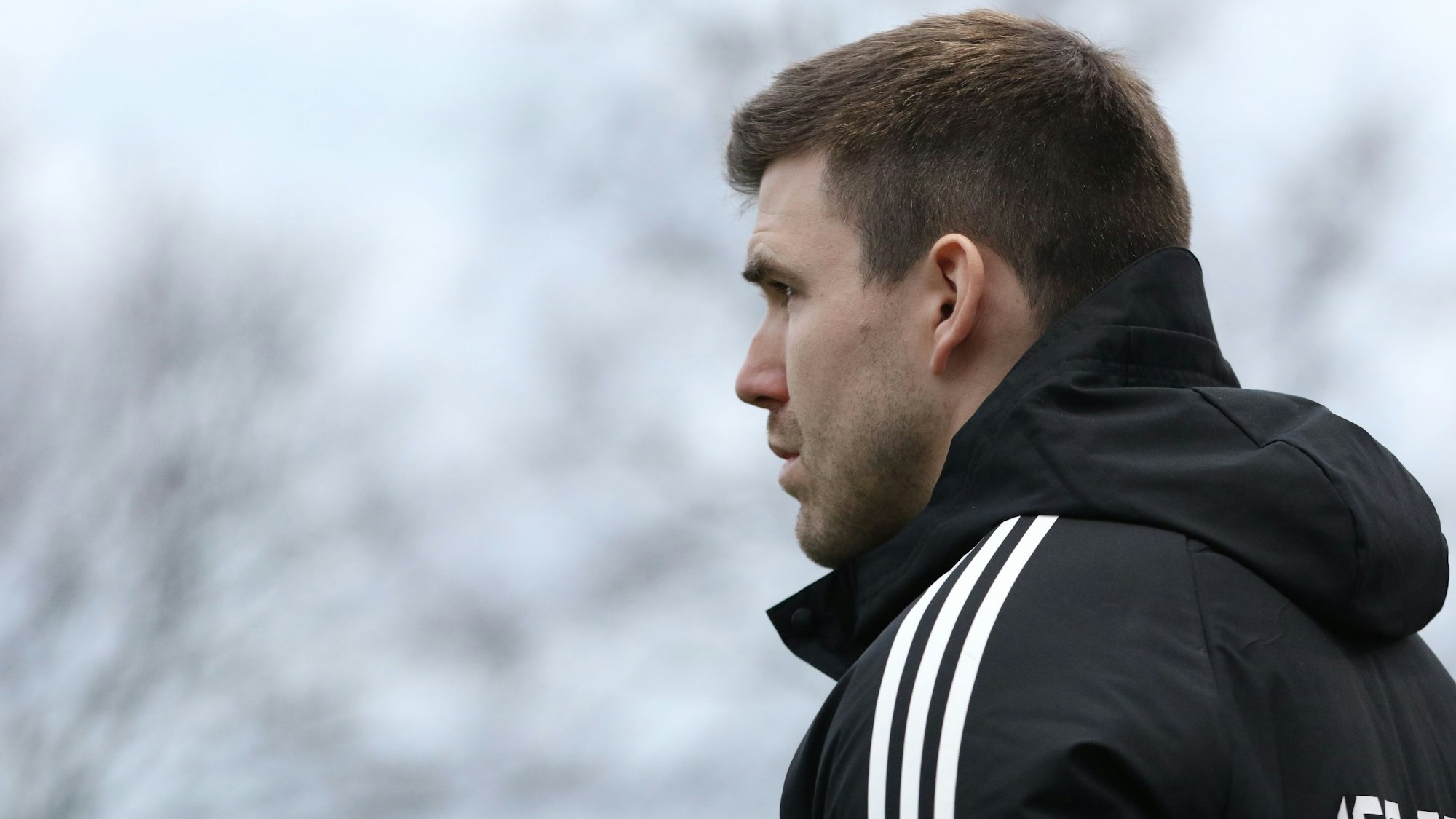 Seitenaufnahme von Marcel Schmitz, im Hintergrund dunkle Wolken.