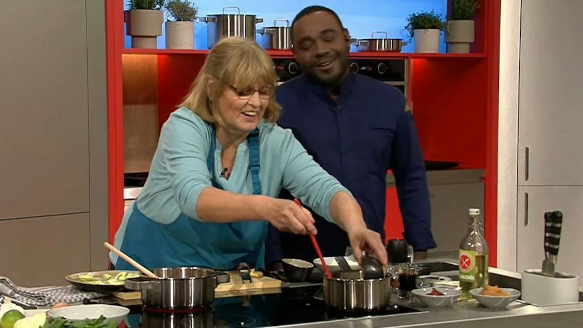 Annemarie Lamß (62) kocht sich in der ZDF-Show „Die Küchenschlacht“ in die Herzen des Publikums – und in das von Moderator Nelson Müller. Auf dem Bild sind die beiden lachend am Herd zu sehen.