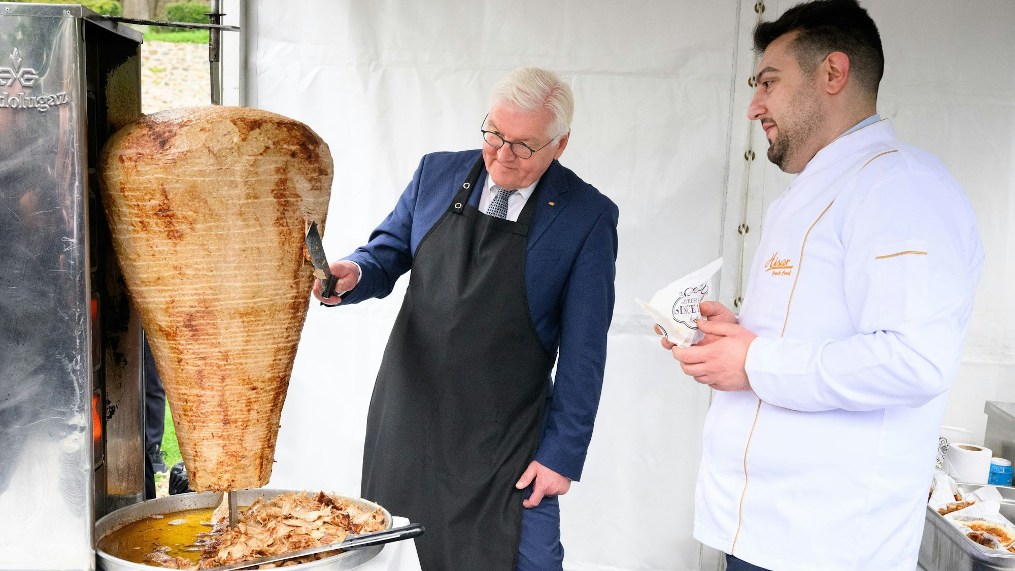 Bundespräsident Frank-Walter Steinmeier (l.) schneidet unter Anleitung des Berliner Gastronoms Arif Keles Döner.