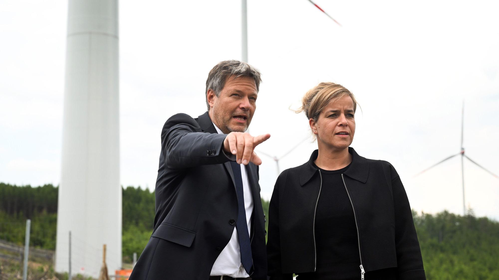 06.06.2023, Nordrhein-Westfalen, Bad Berleburg: Robert Habeck (l), Bundeswirtschaftsminister, und NRW-Wirtschaftsministerin Mona Neubaur (beide Grüne), stehen vor Windrädern zur Stromerzeugung. Die Wittgenstein Gruppe sowie der Landesverband Erneuerbare Energien NRW nehmen den seit Herbst 2022 bestehenden Wald-Windpark Arfeld mit vier Windrädern offiziell in Betrieb. Foto: Federico Gambarini/dpa +++ dpa-Bildfunk +++