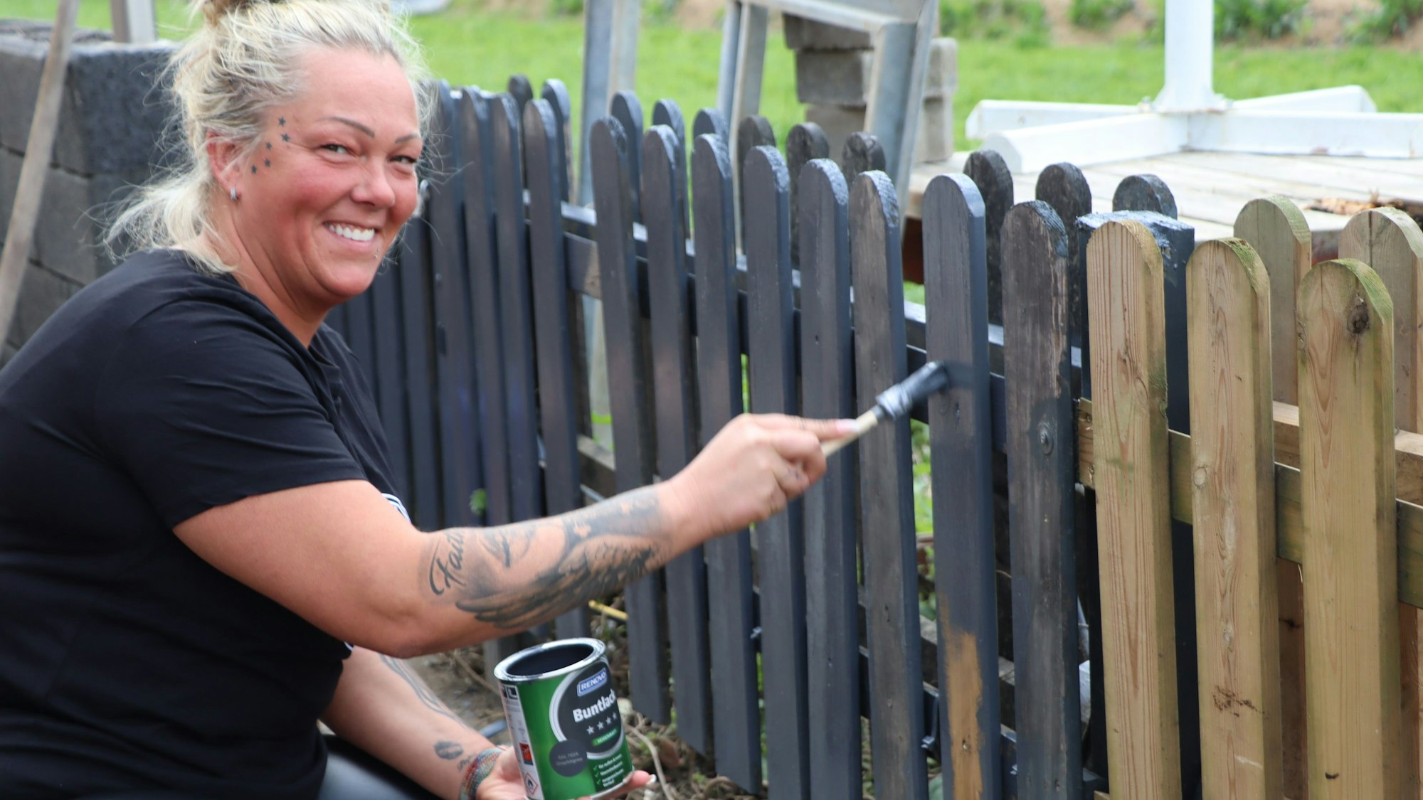 Zu sehen ist Mandy Zöllig, die einen Zaun anstreicht.