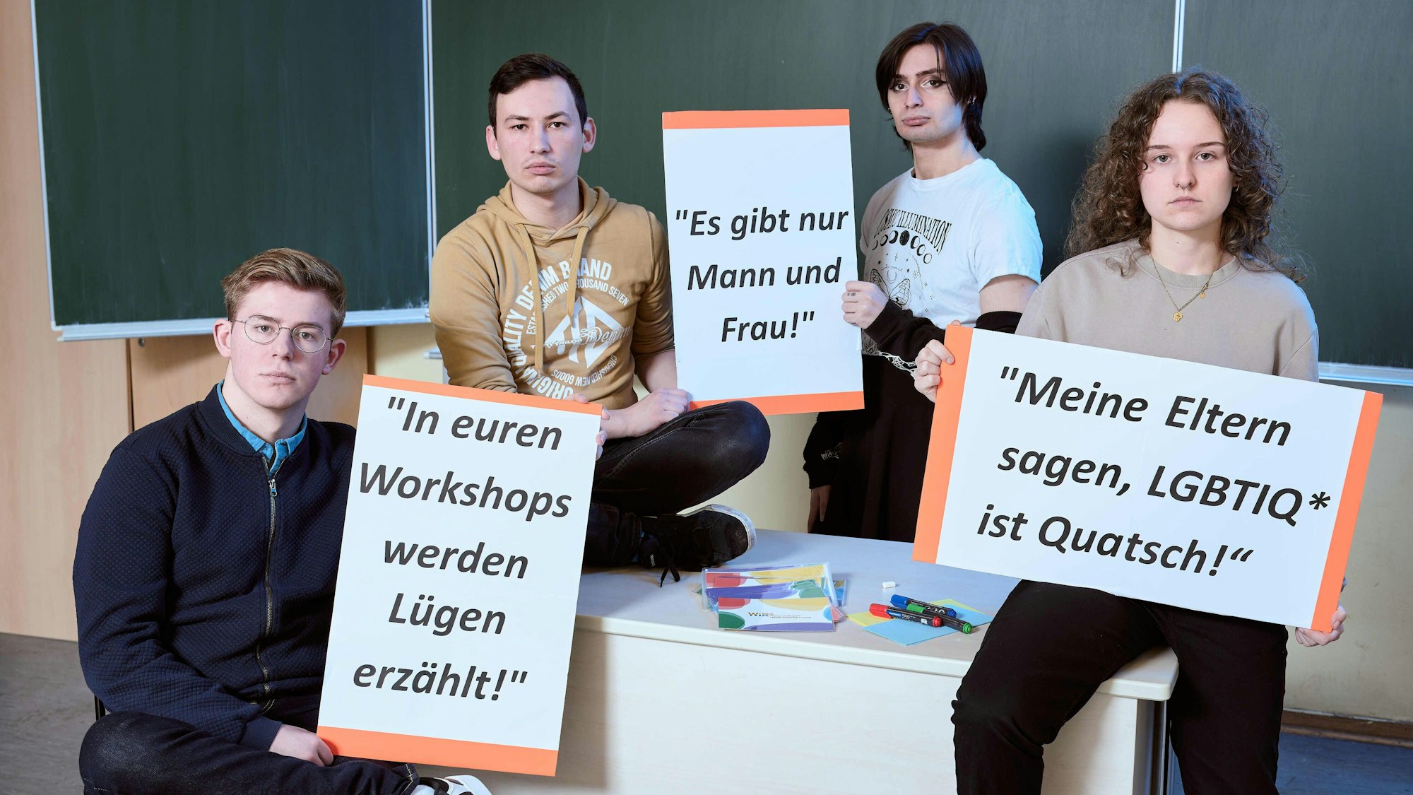 Vier Ehrenamtliche des Anyway halten Schilder mit negativen Äußerungen von Schülern aus ihren Workshops.