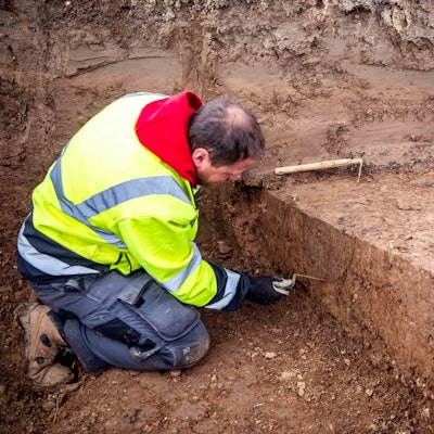 Das Bild zeigt den Grabungstechniker des LVR bei seiner Arbeit. Er kratzt mit einer kleinen Schaufel im Dreck.