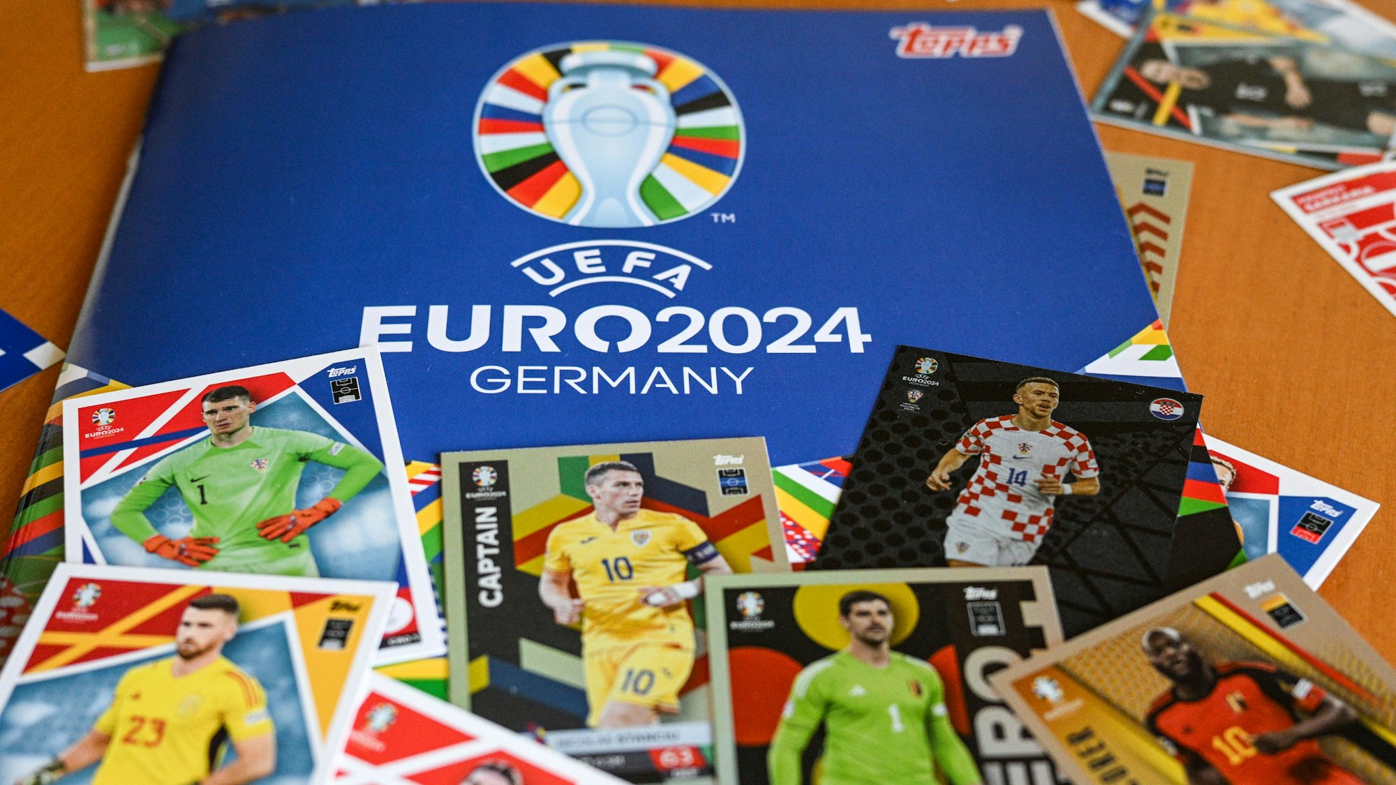 Das Sammelalbum Topps und einige Sticker zum Einkleben liegen zusammen auf einem Tisch.