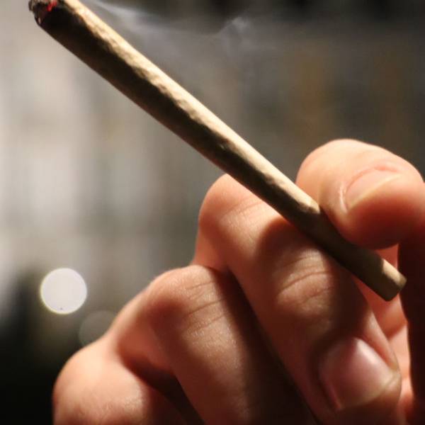 Auf dem Foto ist zu sehen, wie jemand einen Joint in der Hand hält.