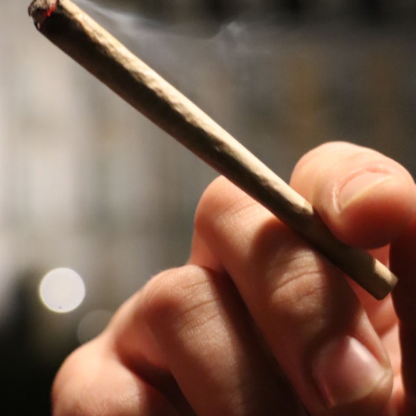 Auf dem Foto ist zu sehen, wie jemand einen Joint in der Hand hält.