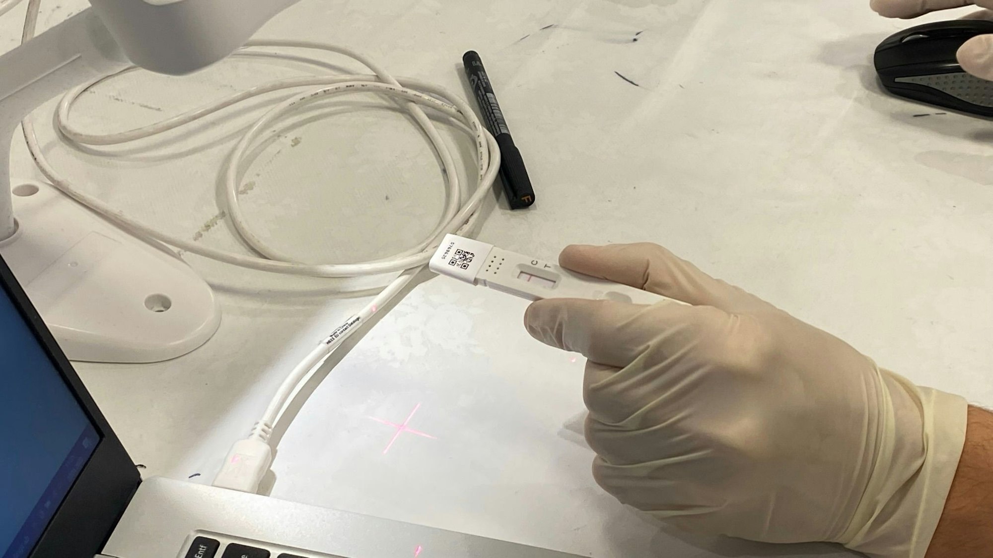 Auf dem Foto ist zu sehen, wie in einem Testzentrum ein Test mit einem QR-Code gescannt wird.