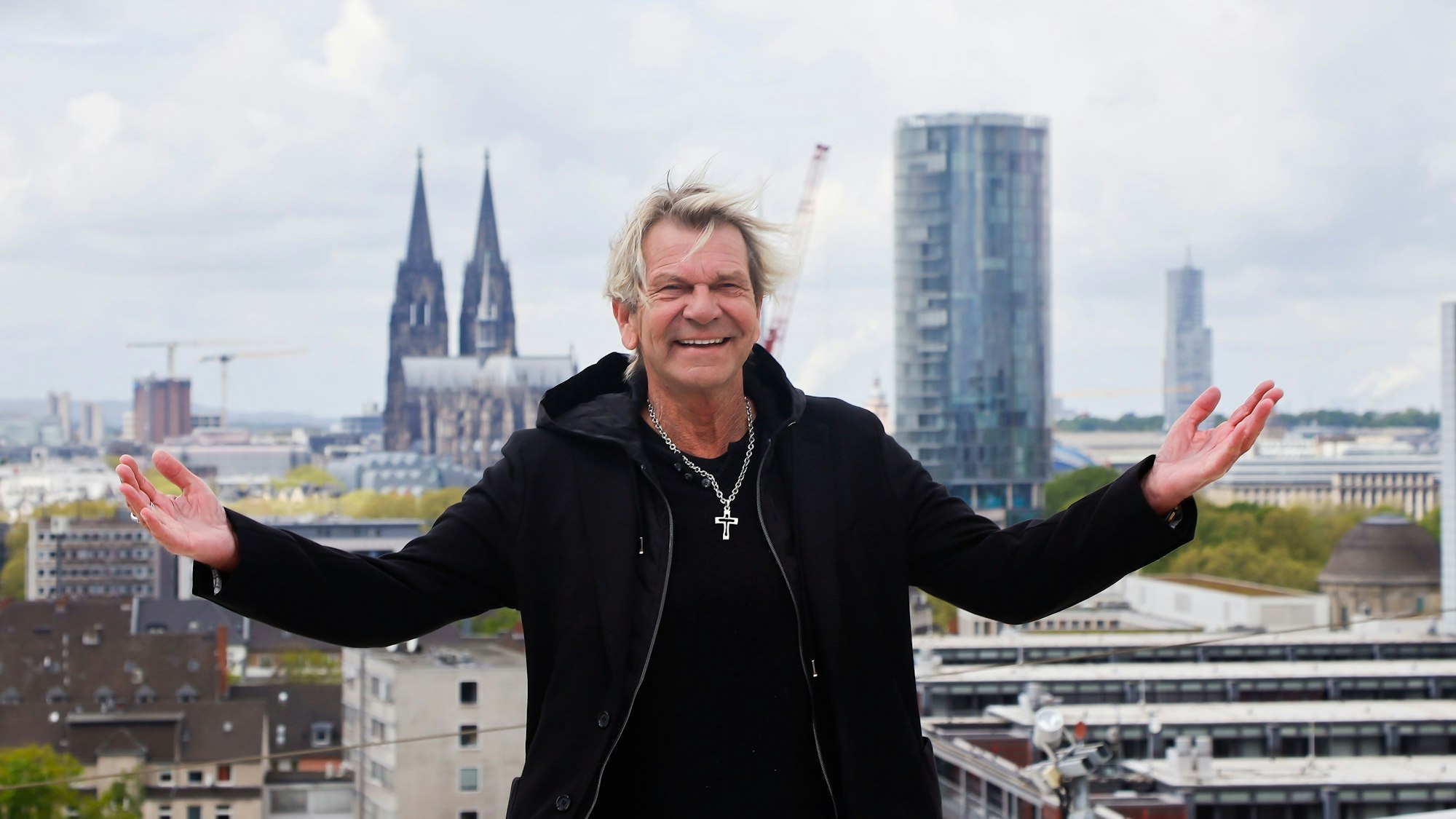 Matthias Reim auf dem Dach der Lanxess-Arena, er lacht und breitet die Arme aus.